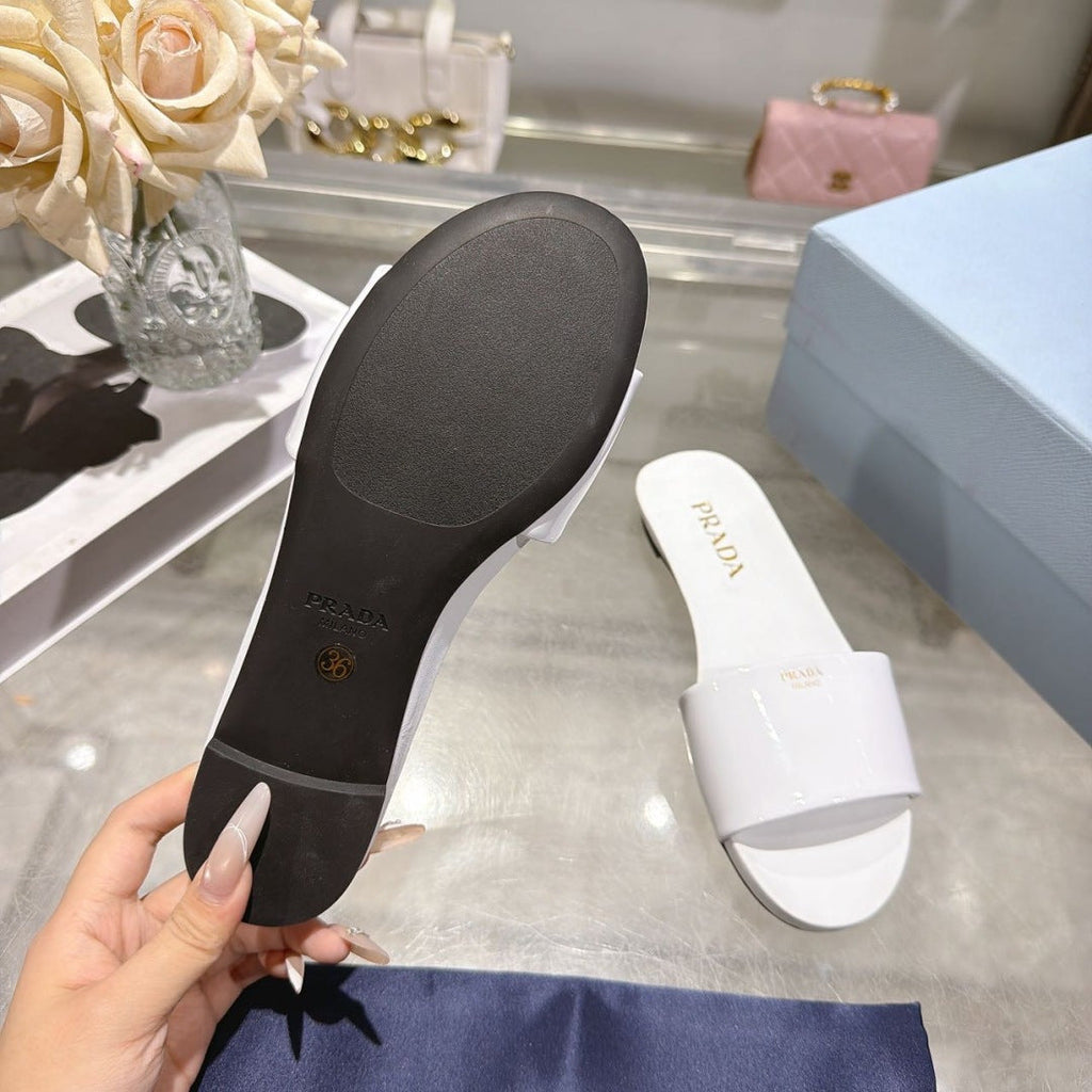 PRADA 26S LOGO EMBOSSED SLIDE SANDALS IN WHITE PATENT CALFSKIN