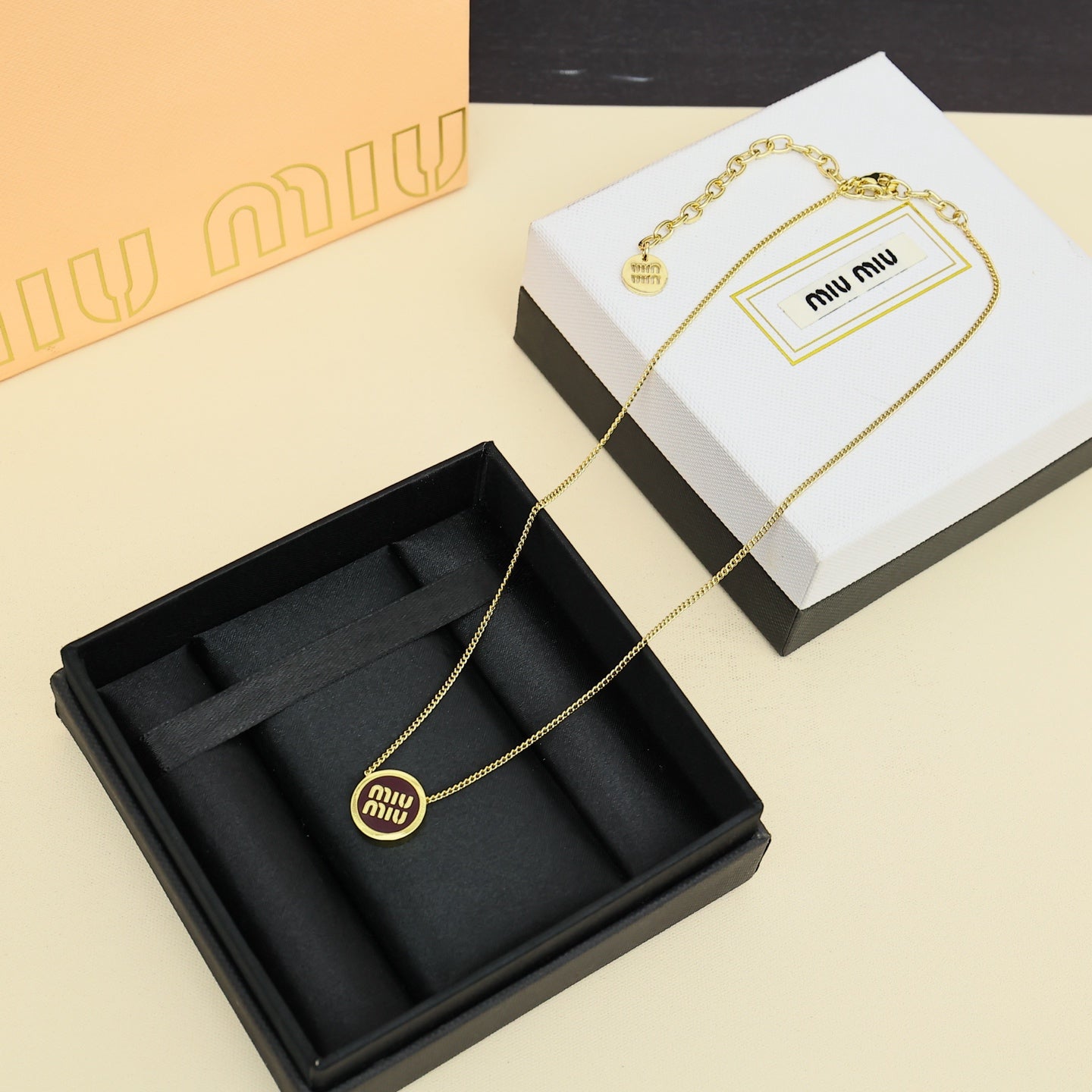 MIUMIU 26S ROUND LOGO PENDANT NECKLACE IN BURGUNDY ENAMEL AND GOLD TONE METAL 612608